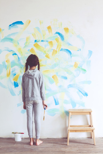 Little girl painting on a wall